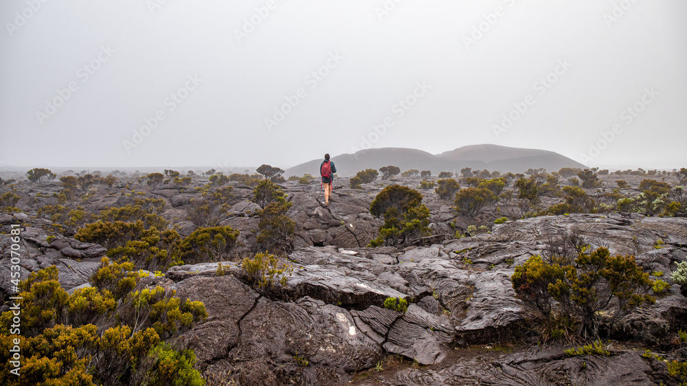 femme marche dans la brume dans la nature, au volcan le piton de la Fournaise à la Réunion.