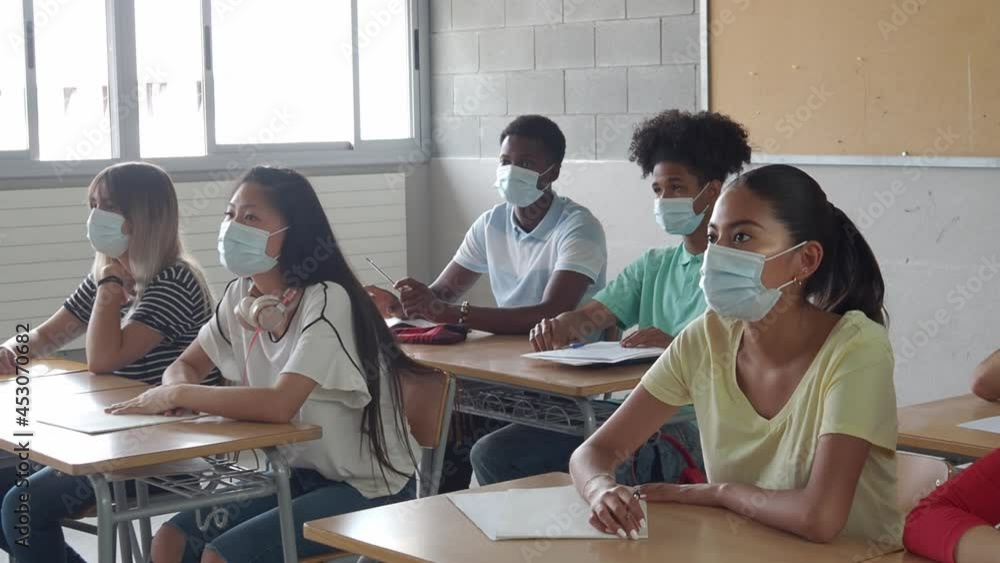 Group of multiethnic teenage students wearing medical mask in class. Group of multiethnic teenage students wearing medical mask in class.