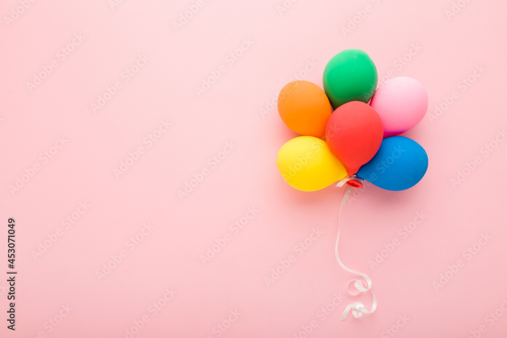 Heap of colorful balloons with white ribbon on light pink table background. Pastel color. Congratulation concept. Empty place for inspirational, emotional text, lovely quote or sayings. Top down view.