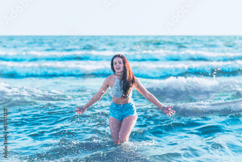 Young woman playing in the sea.woman enjoying in sea water .Cheerful young woman having fun on the summer beach. © ARVD73