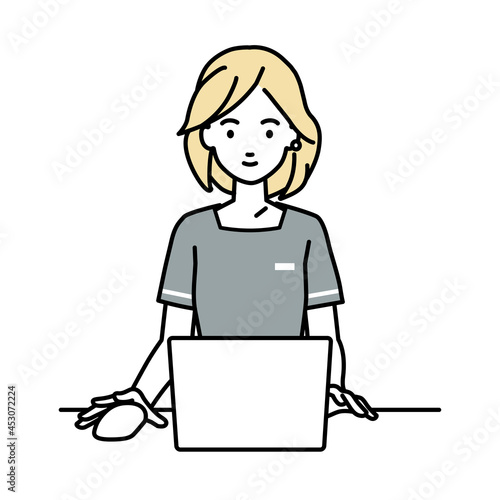 デスクで座ってPCを使っているエステ店員の女性