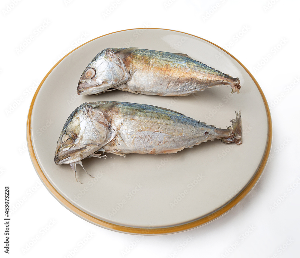 2 mackerel on a plate isolated on a white background, Mackerel is a small fish that is popular for cooking, mackerel meat has many nutrients. Both linoleic acid and cocosahecinoic acid (DHA).