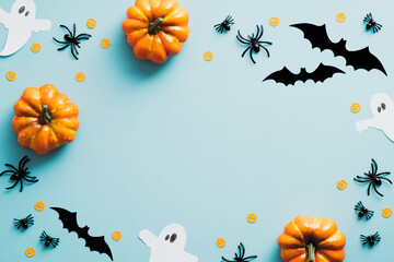 Happy halloween holiday concept. Halloween decorations, bats, ghosts, spiders, pumpkins on blue background. Halloween party greeting card mockup with copy space. Flat lay, top view, overhead.