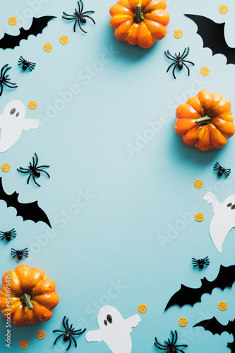 Happy halloween holiday concept. Halloween decorations, bats, ghosts, spiders, pumpkins on blue background. Halloween party poster mockup with copy space. Flat lay, top view, overhead.
