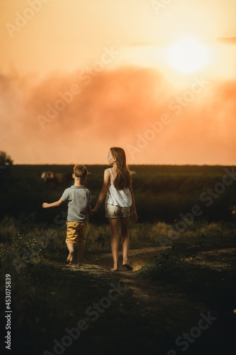 brother and sister walking along the road at sunset