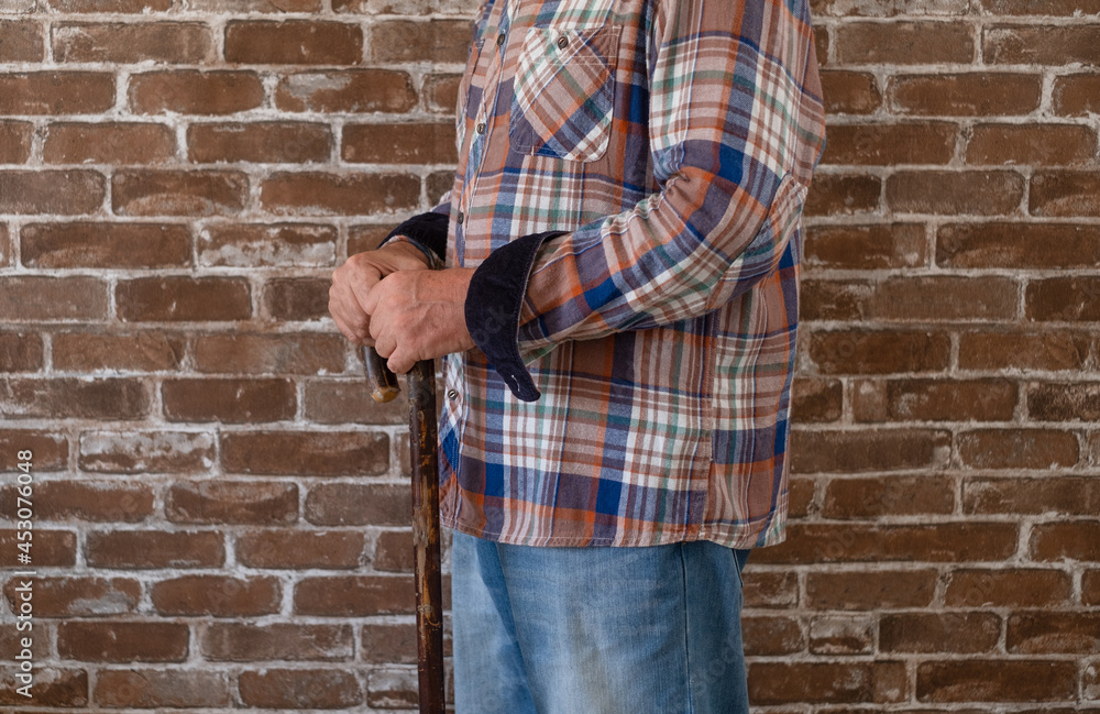 Close-up view of suffering elderly man walking with the help of a cane. Close-up view of suffering elderly man walking with the help of a cane.