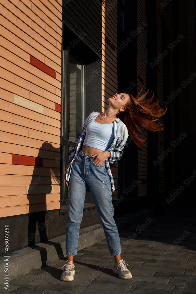 Fototapeta premium an attractive woman with long hair in the city in the sun. urban style