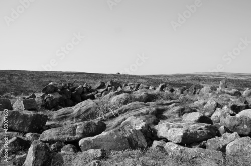 monochrome image of the exposed stones at the top of a cairn known as the millers grave on midgley moor in calderdale west yorkshire with pennine moorland scenery photo