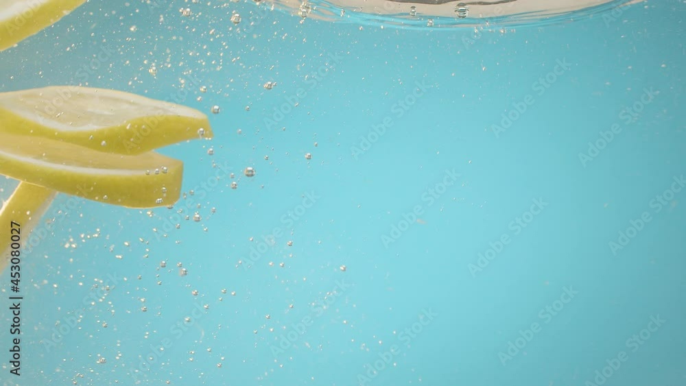 Yellow lemon slice falling in transparent water blue background Fresh fruits Yellow lemon slice falling in transparent water blue background Fresh fruits