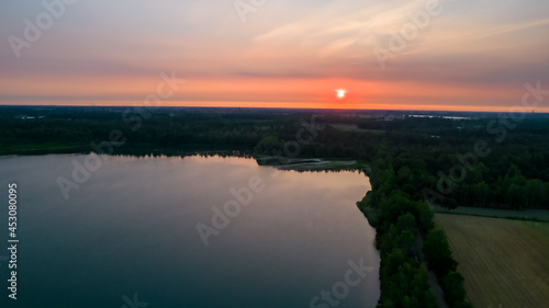 Sunset sky background. Dramatic red and gold sunset sky with evening sky clouds over the forest lake. Stunning sky clouds in the sunset. High quality photo