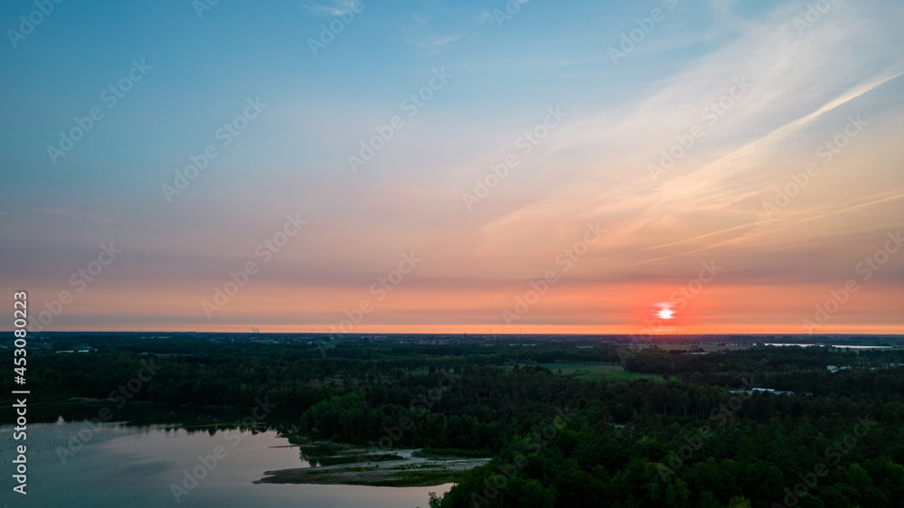 Aerial view of a beautiful and dramatic sunset over a forest lake reflected in the water, landscape drone shot. Blakheide, Beerse, Belgium. High quality photo Aerial view of a beautiful and dramatic sunset over a forest lake reflected in the water, landscape drone shot. Blakheide, Beerse, Belgium. High quality photo
