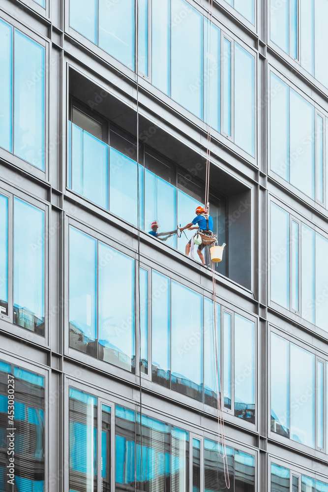 Fototapeta premium Man at work - cleaning windows of a modern skyscraper