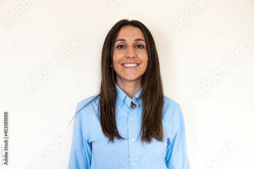 Obraz na płótnie Young and attractive woman looking corporative with a shirt smiling at the camera, looking professional and ready to do bussiness with a white background. Wearing a blue shirt. Latin woman business. w salonie