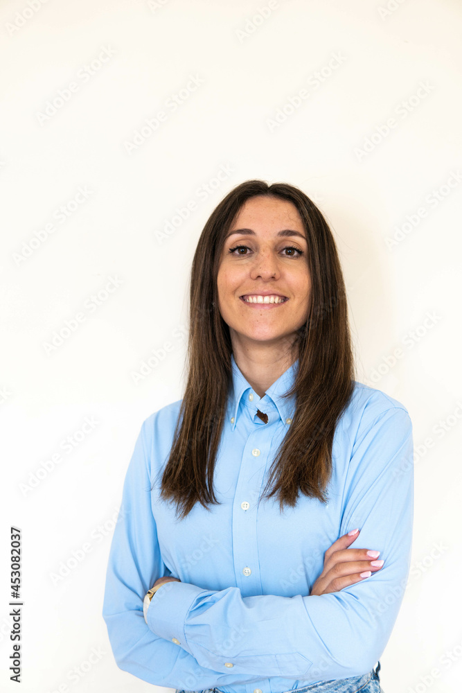 Young and attractive woman looking corporative with a shirt smiling at the camera, looking professional and ready to do bussiness with a white background. Wearing a blue shirt. Latin woman business.