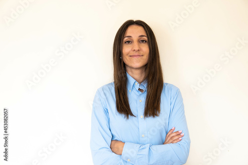 Young and attractive woman looking corporative with a shirt smiling at the camera, looking professional and ready to do bussiness with a white background. Wearing a blue shirt. Latin woman business.