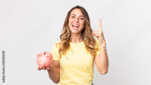 pretty thin woman feeling like a happy and excited genius after realizing an idea and holding a piggybank photo