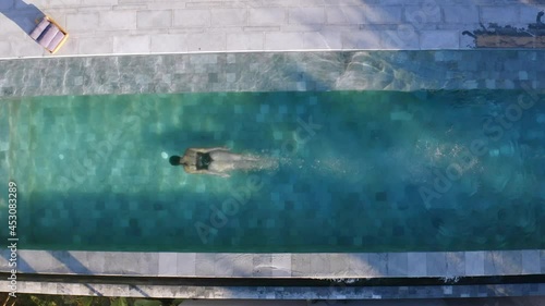 aerial shot of woman jumping into the swimming pool at the luxury villa, she swims under the water