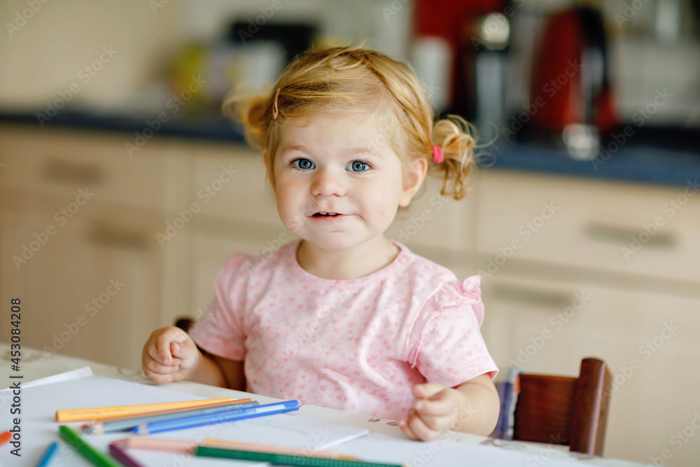Cute adorable baby girl learning painting with pencils. Little toddler child drawing at home, using colorful felt tip pens. Healthy happy daughter experimenting with colors at home or nursery. Cute adorable baby girl learning painting with pencils. Little toddler child drawing at home, using colorful felt tip pens. Healthy happy daughter experimenting with colors at home or nursery.