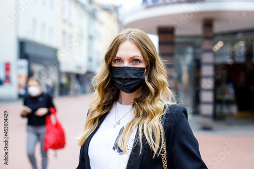 Portrait of young beautiful woman wearing medical mask as protection against corona virus. Covid pandemic time in Europe and in the world. Safety for people. Woman in summer city. © Irina Schmidt