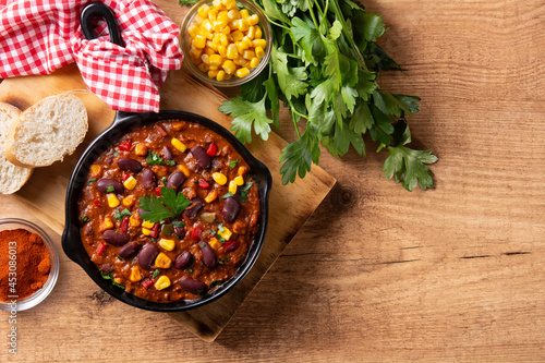 Traditional mexican tex mex chili con carne in iron pan on wooden table