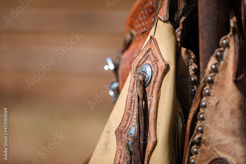 Cowboy chaps hanging on a fence with focus on decorative detail and copy space photo