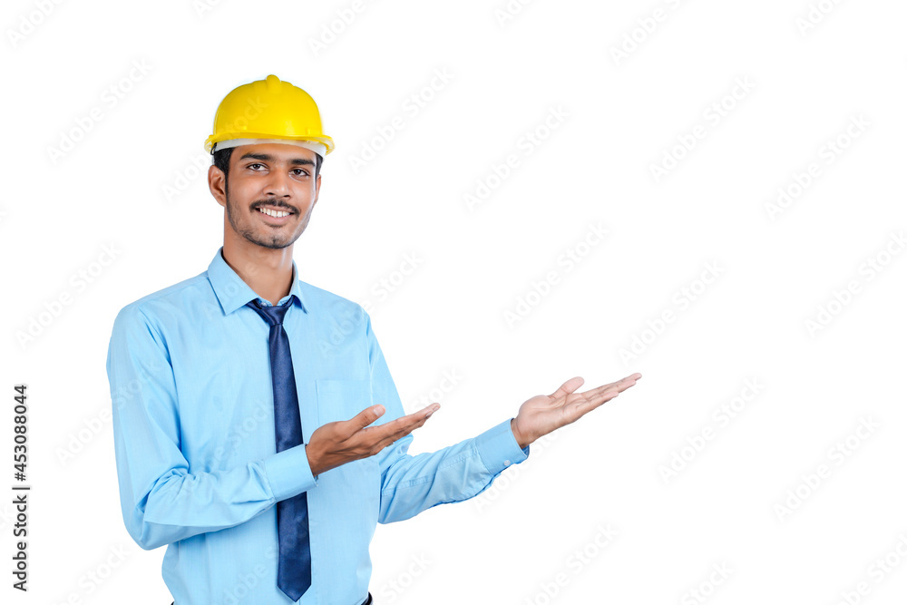 Young Indian male engineer wearing yellow color hard hat on white background. Young Indian male engineer wearing yellow color hard hat on white background.