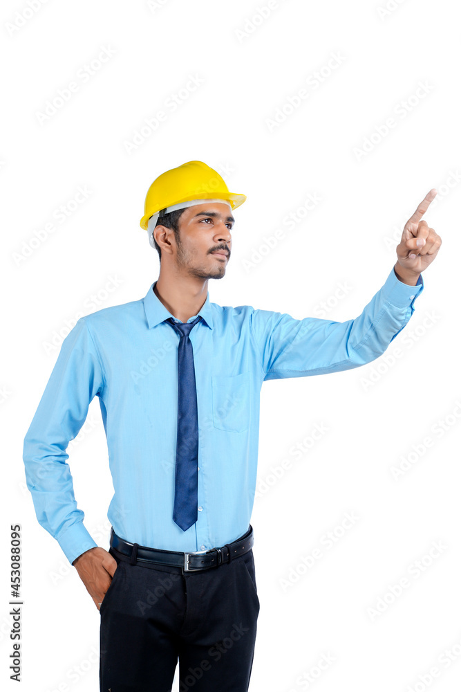 Young Indian male engineer wearing yellow color hard hat on white background. Young Indian male engineer wearing yellow color hard hat on white background.