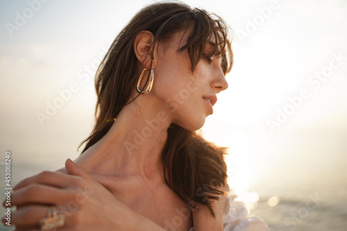 Canvas Print Portrait of young brunette haired woman at the beach at sunset