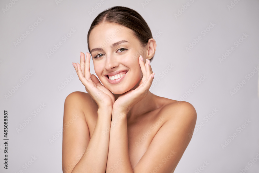 Beautiful Young Woman with Clean Fresh Skin standing over light grey background Beautiful Young Woman with Clean Fresh Skin standing over light grey background