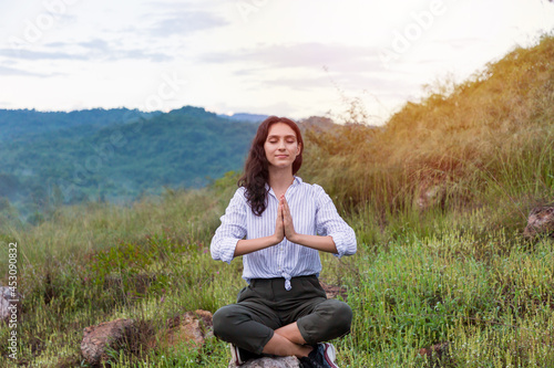 Young woman doing meditate yoga with eyes closed in the mountain on forest background. Female practicing doing yoga outdoor