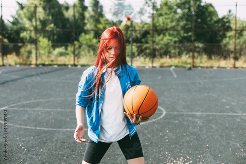 A young basketball player is training on an outdoor basketball court, a teenage girl is playing basketball. Basketball, sports