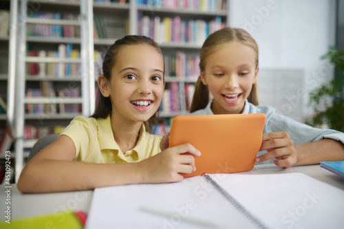 Cheerful friends with a tablet computer sitting at the desk
