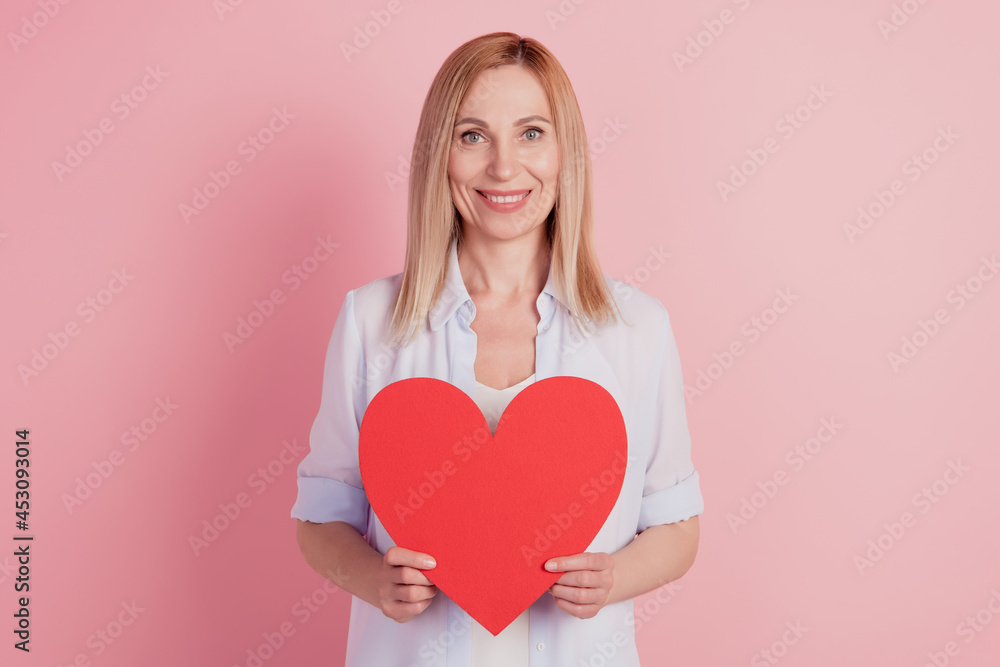 Photo of young woman holding in hand large big heart valentine day love romance isolated over pink background Photo of young woman holding in hand large big heart valentine day love romance isolated over pink background