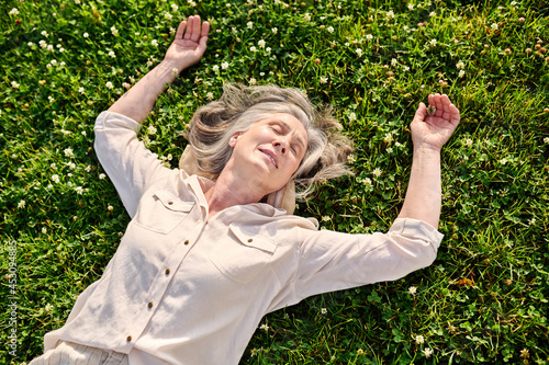 Retired woman relaxing on green lawn