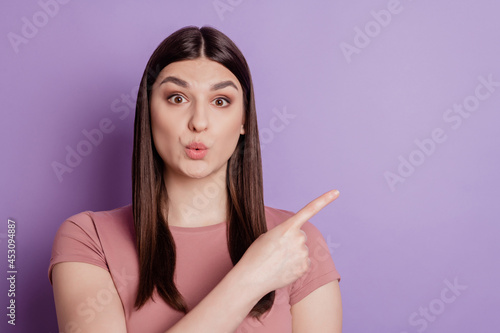 Portrait of positive cheerful girl point index finger copyspace recommend select ads promotion isolated over violet color background
