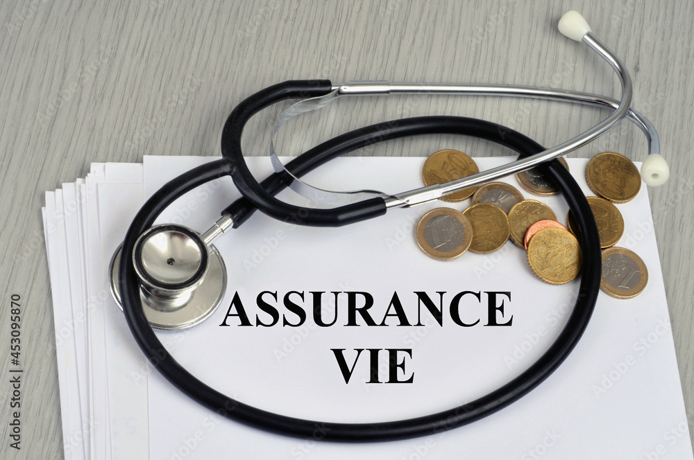 Concept d'assurance vie avec un stéthoscope et de l'argent en cash posés sur un contrat en français Concept d'assurance vie avec un stéthoscope et de l'argent en cash posés sur un contrat en français
