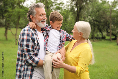 Cute little boy and grandparents spending time together in park
