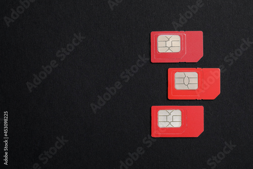 Red SIM cards on black background, flat lay. Space for text