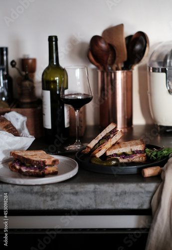 Meat and pickles sandwiches and glass of red wine on concrete  table photo