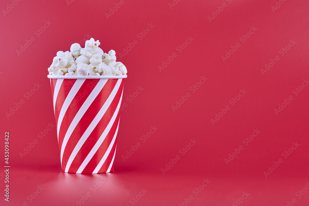 Red glass with popcorn on a red background