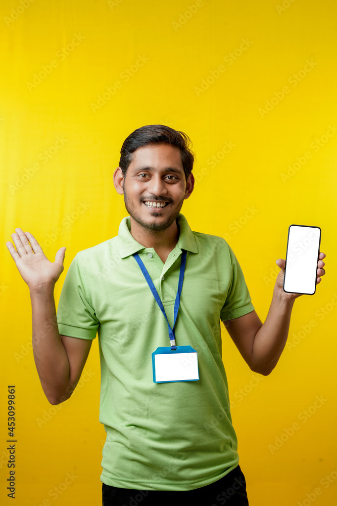 Portrait of a excited happy young delivery man in t shirt and showing smartphone over yellow background. Portrait of a excited happy young delivery man in t shirt and showing smartphone over yellow background.