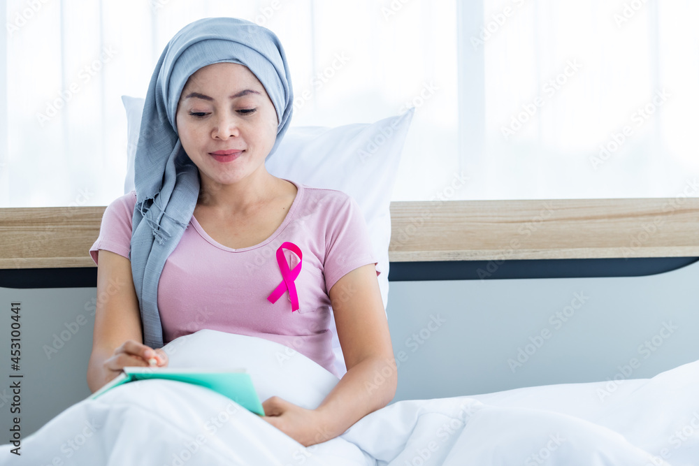 a asian women disease mammary cancer patient with pink ribbon wearing headscarf After treatment to chemotherapy with Take notes in a notebook on bed In the bedroom at the house,healthcare,medicine a asian women disease mammary cancer patient with pink ribbon wearing headscarf After treatment to chemotherapy with Take notes in a notebook on bed In the bedroom at the house,healthcare,medicine