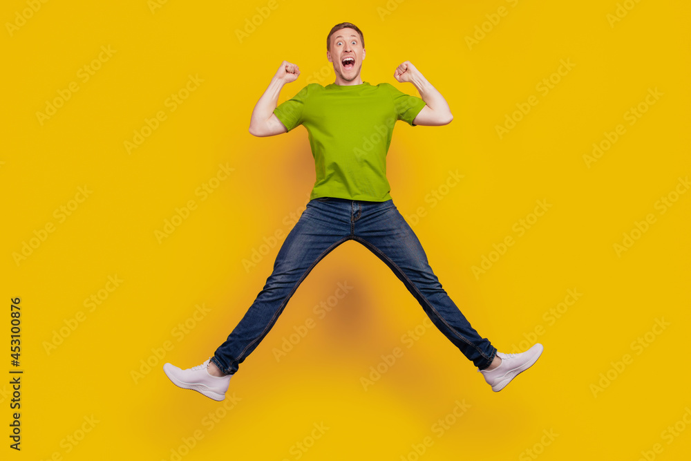 Full size photo of nice attractive cheerful optimistic guy having fun jump up ecstatic winner isolated over yellow background