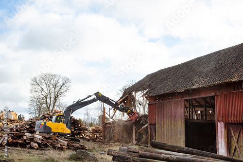 Earth mover demolishing old barn photo