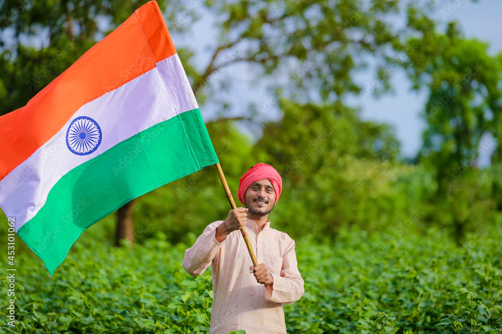 young indian farmer holding indian flag in hand at agriculture field ...