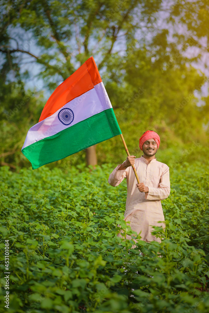 young indian farmer holding indian flag in hand at agriculture field ...