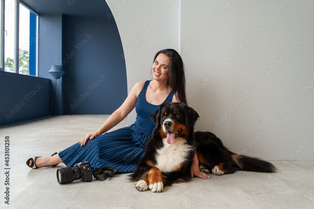 A girl in a blue dress with Berner Sennenhund in an embrace lies on the floor A girl in a blue dress with Berner Sennenhund in an embrace lies on the floor