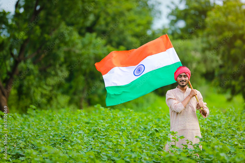 young indian farmer holding indian flag in hand at agriculture field ...