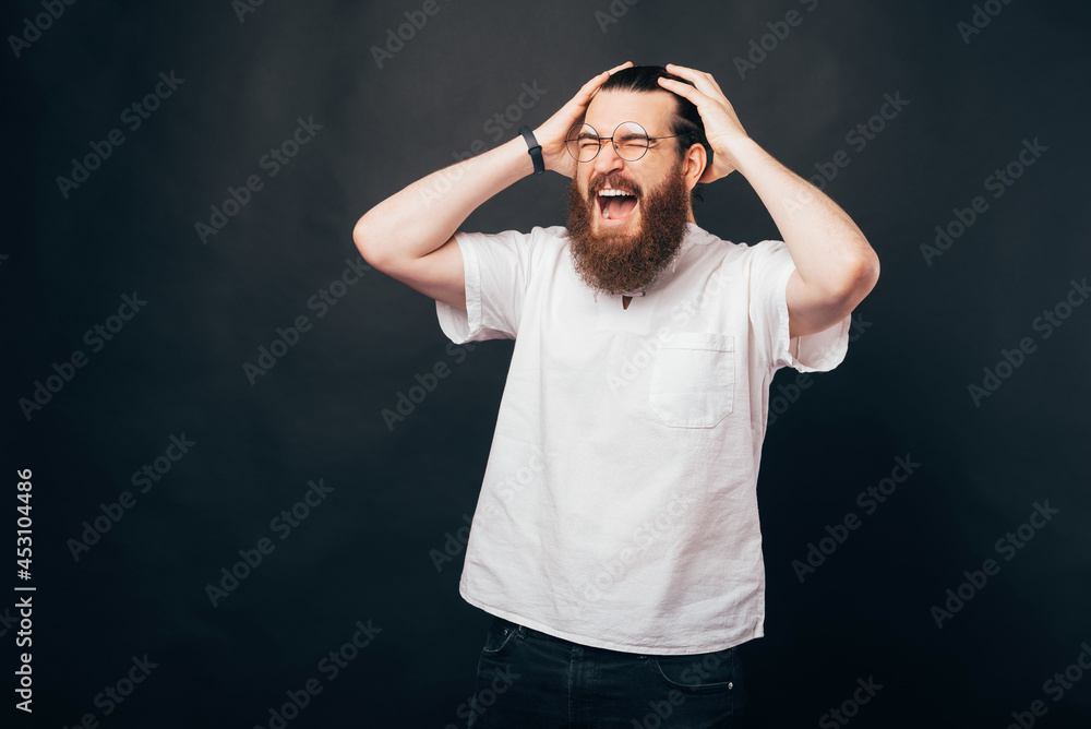 Young man is touching his head and screaming with eyes closed. Young man is touching his head and screaming with eyes closed.