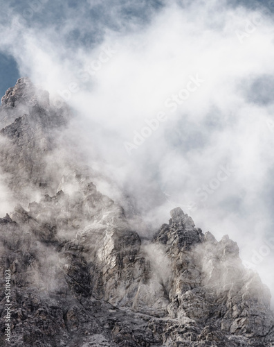 Beautiful snow-capped rocky mountains surrounded by clouds. Mobile phone screensaver. High quality photo